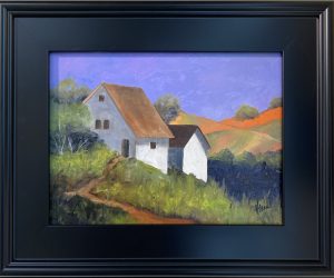 Framed landscape painting of a white farmhouse on a grassy hill, with rolling hills and orange sunlight in the background beneath a lavender sky